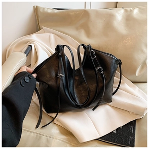 Detail of black leather shoulder bag showing delicate straps and silver metal buckles