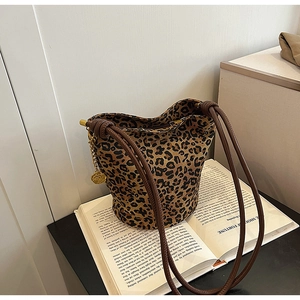 Detailed view of leopard print tote bag with golden rose charm on a book background