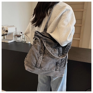 Detail showing the gray washed denim tote bag texture and pockets on a casual model