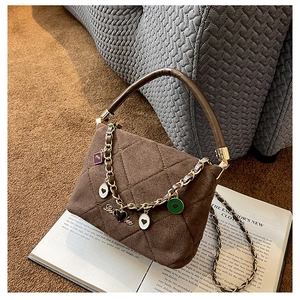 Detailed macro of brown quilted suede handbag with enamel heart charms and gold chain