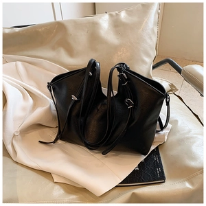 Close-up of black leather tote bag featuring silver hardware and durable dual handles