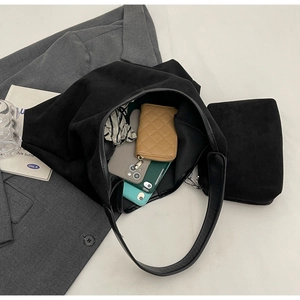 Détail d'un sac seau en suédine noire montrant l'intérieur spacieux avec un portefeuille