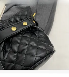 Detail of black quilted bucket bag featuring soft leather texture and golden rivets