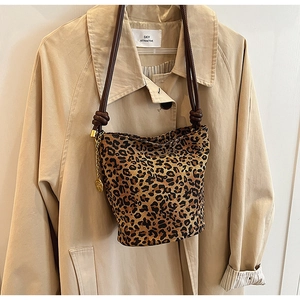 Detailed macro view of leopard print tote bag with brown woven strap and gold metal hardware