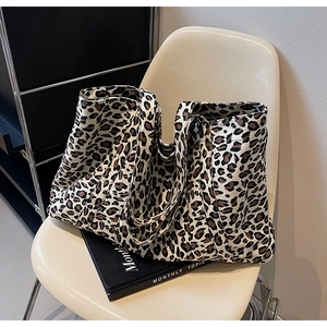 Detail view of large leopard print tote bag placed on a white chair in a minimal room