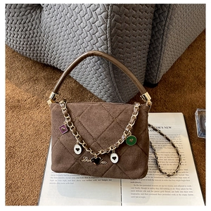 Detail view of brown quilted suede handbag with heart charms on gold chain link