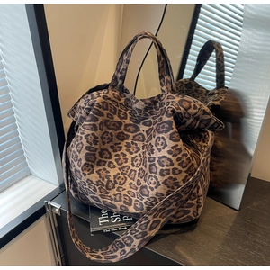 Detail of a large leopard print tote bag with adjustable strap on a dark tabletop surface