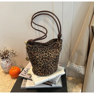 Detail of leopard print canvas tote bag with brown knotted handles and gold chain