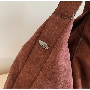 Detail of dark brown suede hobo bag with polished oval silver metal buckle accent