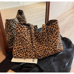 Detail of a large leopard print canvas tote bag with wide handles on a silk background