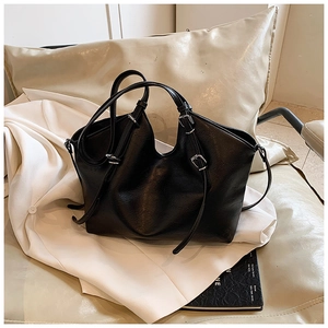 Detail view of black matte leather tote bag with adjustable straps and metal buckles