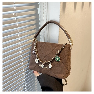 Detailed view of brown velvet quilted handbag featuring colorful heart pendants and top handle