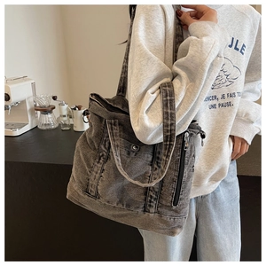 Detail of grey washed denim tote bag with side zipper pocket in casual cafe setting