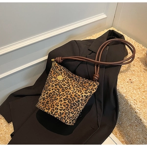 Detail of leopard print tote bag featuring thick rope handles and gold rose charm detail