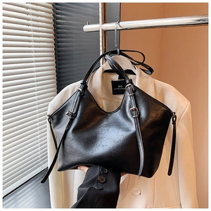 Detail shot of black leather tote bag featuring a V-shaped opening and adjustable straps
