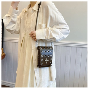Close-up of dark brown leather crossbody bag with punk metal studs and skull cross detail