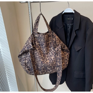 Close-up of leopard print tote bag fabric with long shoulder strap on a hanger