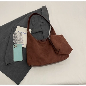 Détail du sac hobo en daim marron foncé avec pochette zippée assortie sur un blazer