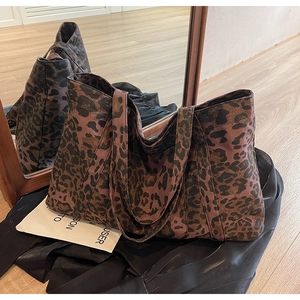 Detail of leopard print tote bag with wide handles and soft fabric texture by a mirror