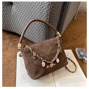 Detail of a brown quilted suede handbag with gold heart charms and metal chain decoration