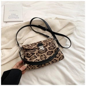 Close-up of leopard print crossbody bag with silver rotating metal lock on fabric