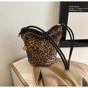 Detail of leopard print tote bag with black tied strap and golden camellia charm