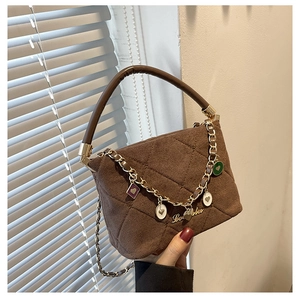 Detail of brown suede crossbody bag featuring diamond quilting and heart charm