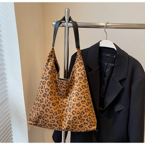 Gros plan du sac cabas imprimé léopard avec poignées en cuir sur un support en métal