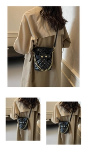 Detail of black quilted bucket bag featuring gold chain strap and metallic studs