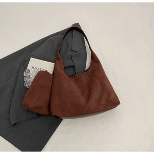 Vue détaillée de la texture du sac en daim marron foncé et de sa petite pochette assortie