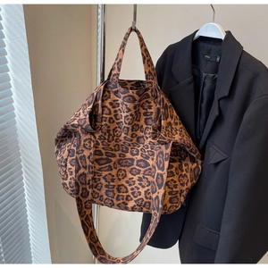 Detail of a large leopard print canvas tote bag with wide shoulder straps for travel
