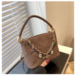 Detail of brown quilted faux suede handbag featuring golden chain with heart charms