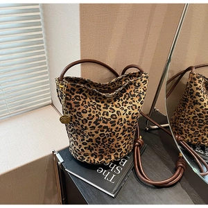 Detail of leopard print tote bag with brown leather straps and gold flower charm
