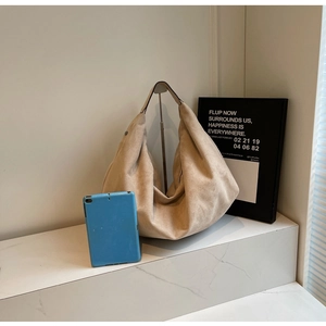 Detail showing high-capacity beige suede hobo bag with tablet for size scale comparison