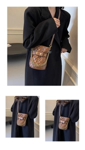 Detail of brown quilted bucket bag with gold chain strap and rivet embellishments