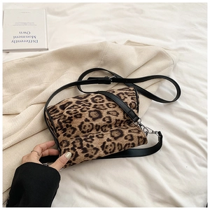 Close-up of leopard print crossbody bag with plush texture and black faux leather strap
