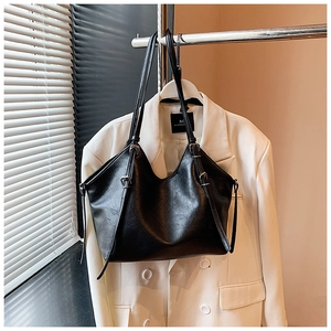 Close-up of black lychee-textured faux leather tote bag with silver metal buckles