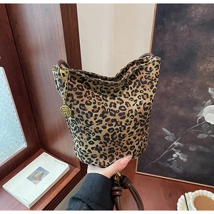 Detail of leopard print tote bag featuring a gold rose pendant and brown leather handle