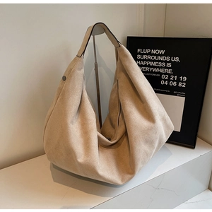Close-up of beige suede hobo tote bag featuring side metal zipper and rivet details
