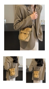 Detail of light brown quilted bucket bag featuring gold chain and adjustable strap