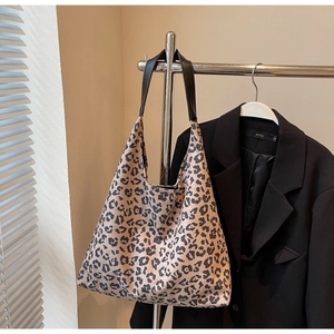 Détail d'un sac cabas à imprimé léopard avec des bandoulières en cuir noir suspendu