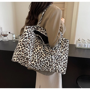 Detailed view of leopard print tote bag being carried over the shoulder in a cafe setting