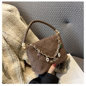 Detail of dark brown quilted suede handbag with golden chain and heart-shaped charms