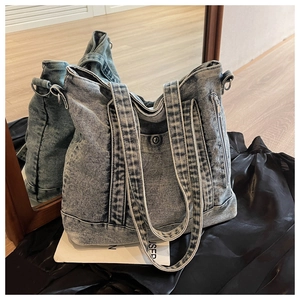 Detailed view of washed blue denim tote bag with side metal zipper and dual strap design
