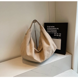 Macro detail of high-capacity beige suede hobo bag on elegant marble surface