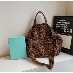 Macro detail of large leopard print canvas tote bag showing texture and long strap attachment
