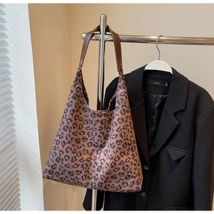 Détail du sac hobo à imprimé léopard avec bandoulière en cuir marron sur un cintre en métal