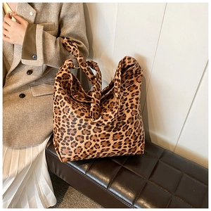 Detail of leopard print canvas tote bag featuring metal rings and decorative shoulder strap