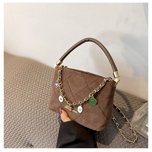 Detail of brown quilted velvet handbag with gold heart charms and chain strap