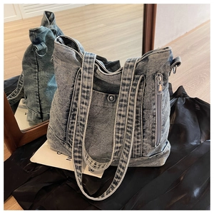Detailed close-up of blue washed denim tote bag featuring side zipper and front snap pocket
